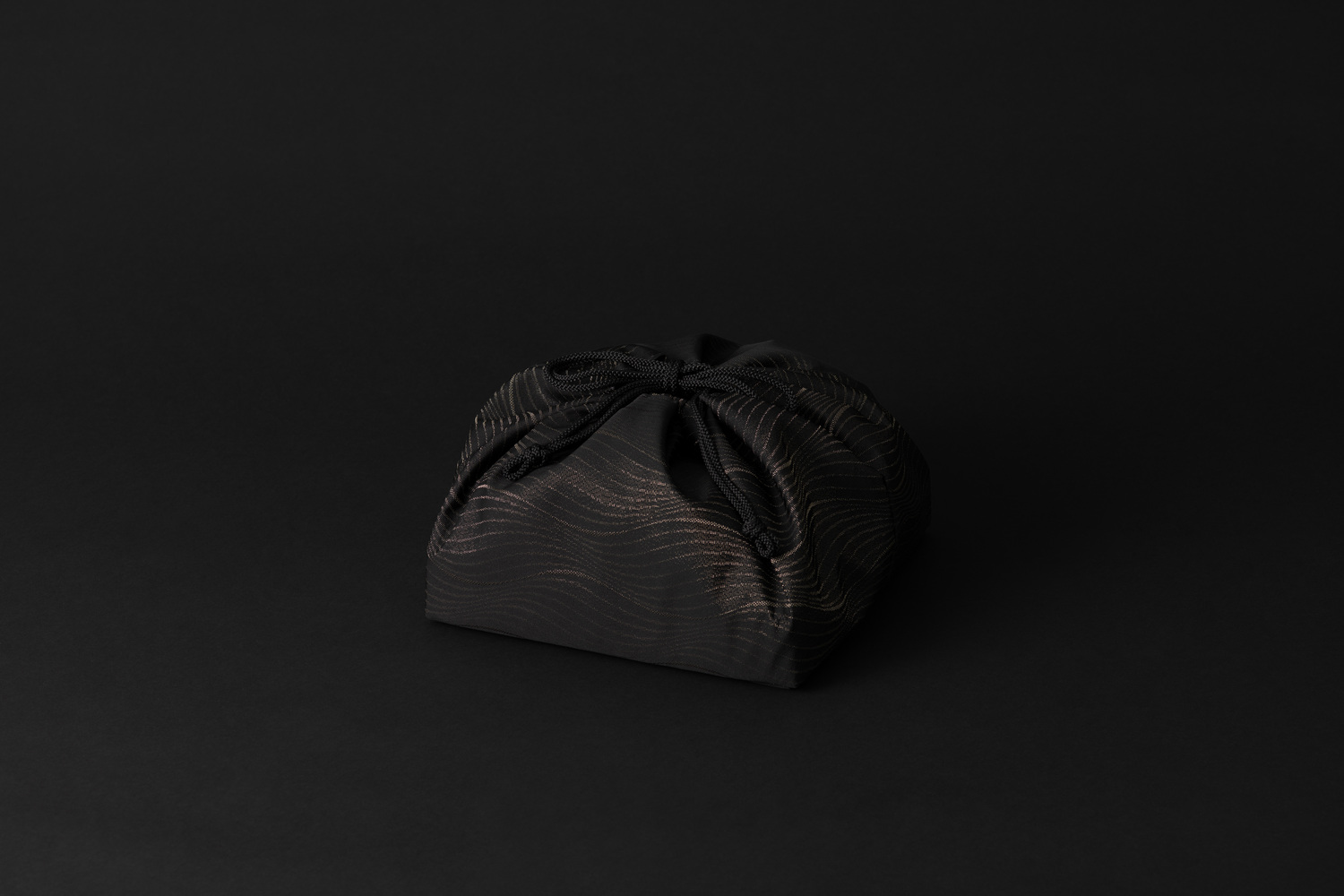 closed Shingen Tango Chirimen silk pouch with black-and-gold wave pattern